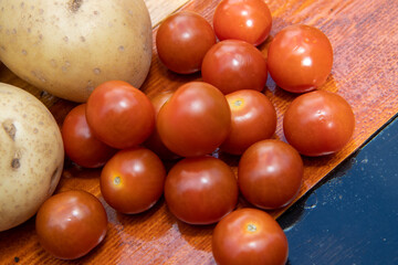 A wooden chopping board with food ingredients for making a meal including cherry tomatoes and...