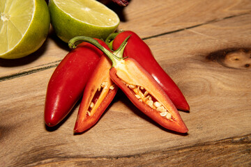A wooden chopping board with food ingredients for making a meal including limes and peppers
