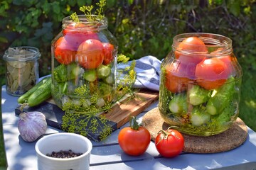 Preparation of pickled cucumbers and tomatoes with herbs, garlic and dill. Home canning, fermented vegetables.