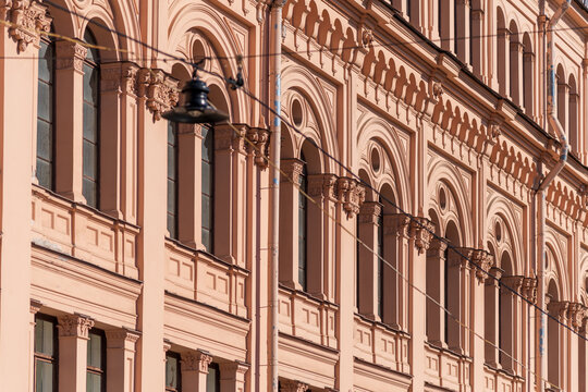 Side view of traditional ornate terracotta coloured facade with group of windows on wall of residential building in Saint Petersburg, Russia. Copy space. Architecture and city street background theme.
