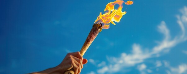 A person holding a torch in a blue sky. Free copy space for text.