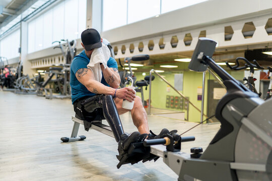 Man Resting on Rowing Machine in Gym