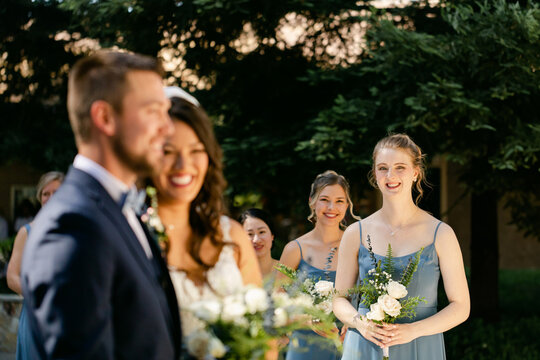 Smiling Bridesmaids Look on as Bride and Groom are Married.
