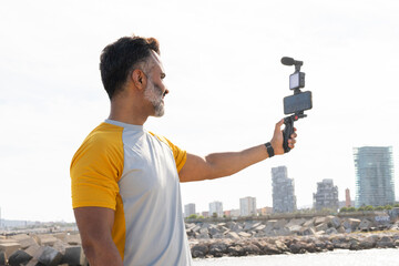 Man recording with smartphone gimbal at seaside