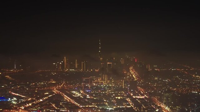 Airplane flying over Dubai Skyline illuminated at night.  Airplane Jet plane taking off from Dubai airport at night