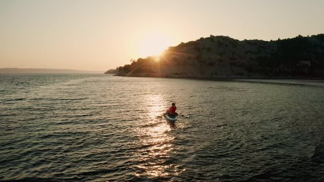 Tourist sits on paddle board navigating in calm sea at sunset. Water with sunpath activity reveals fascinating views of nature on summer weekends