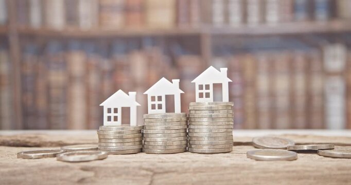 Mortgage loan or home equity loan, financial concept : Tiny model residential house perched atop coin stacks, depicting home loan or borrowing money to purchase a new home for first time homebuyer.