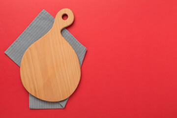Cutting board with napkin on color background, top view