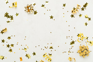 Golden gift boxes and confetti on concrete background, top view
