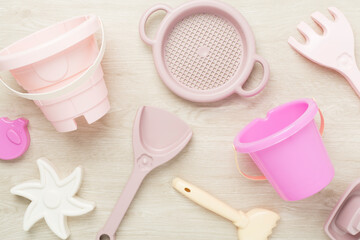 Cute toys for playing with sand on wooden background, top view