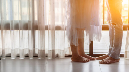 The young couple stood by the window in the morning congratulating the woman on the verge of giving birth and discussing the schedule of childbirth and health care during her pregnancy.