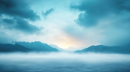 Fototapeta premium Serene landscape with misty mountains and a calm lake under a blue sky.