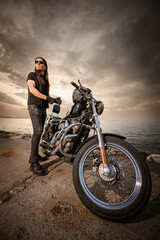 Obraz premium Man with Chopper Motorcycle by the Sea at Sunset..