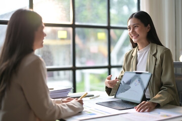 Business Meeting in Modern Office with Two Professional Women Discussing Work and Analyzing Data on a Laptop