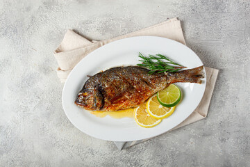 baked dorado fish, in the oven, fried dorado, with spices and herbs, on a white plate, top view, homemade, no people,