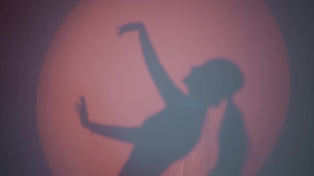 A dancing lady's shadow reflecting on the wall, moving hands slowly and gently against a red background. The silhouette captures a graceful and artistic motion