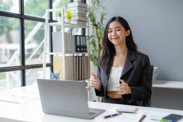 Smiling asian businesswoman gesturing while having video call on laptop in modern office