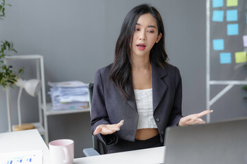 Confident asian businesswoman video calling at office desk, showcasing modern approach to communication. Thriving career with internet technology