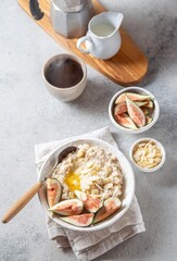 A wholesome bowl of oatmeal topped with fresh figs and sliced almonds, set on a rustic linen cloth. Accompanying small bowls of figs and almonds enhance the cozy breakfast scene