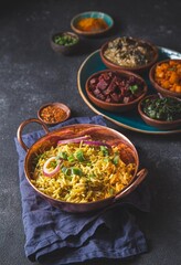 An assortment of vibrant, flavorful vegetarian Pakistani Indian dishes, including biryani rice, served in small wooden bowls on a rustic platter, garnished with fresh herbs and onions