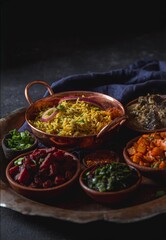 A plate featuring rice biryani and a variety of vegetarian Indian and Pakistani dishes.