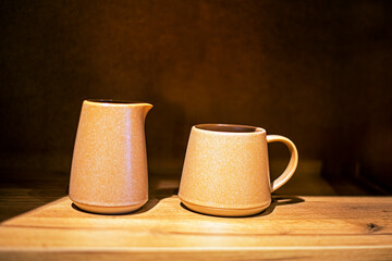 ceramic dishes cup and coffee pot on a brown background. Stylish dishes