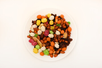Sweet assorted nuts and dried fruits in a plate on a white background.