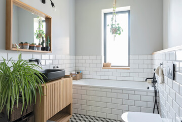 Modern bathroom with white tiles and sink on wooden cabinet in loft apartment in industrial design.
