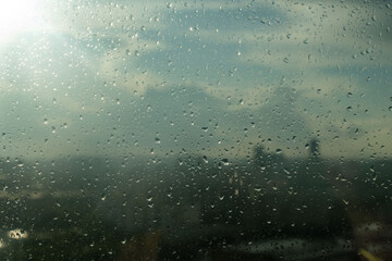 Raindrops fall on the window of a house in a big city. Close-up of slow rain, rainy day, heavy downpour. Rain in the city, background for a sad mood
