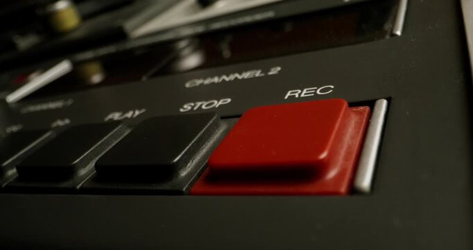 A man presses the record button on a professional tape recorder in the studio. Close-up of his hand, an unrecognizable person