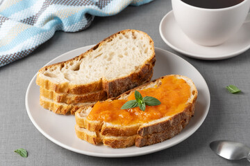 Sandwich with apricot jam and mint on a gray table. Tasty breakfast