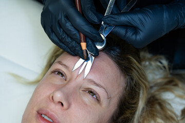 Beautician sketches and measures for microblading treatment