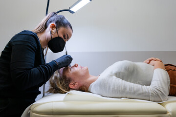 Beautician performing microblading on client’s eyebrows