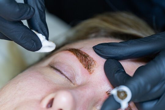 Beautician performs microblading on client's eyebrows