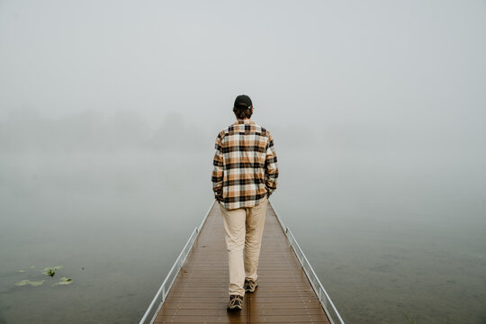 Man walking on foggy pier in tranquil nature scene