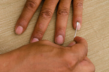 a multiracial man uses a cuticle pusher to give himself a manicure