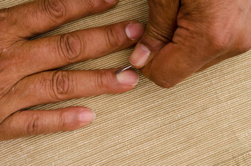 a multiracial man uses a cuticle pusher to give himself a manicure