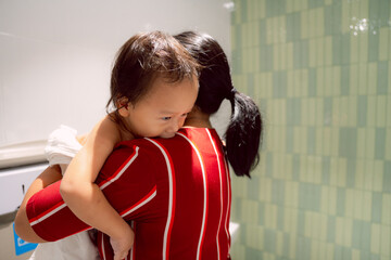 An adorable Asian boy is being dressed or having dressed put on by his mom on the Baby Changing...