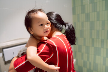 Portrait of Little boy getting dressed in family bathroom, public restroom, mother hugging toddler...