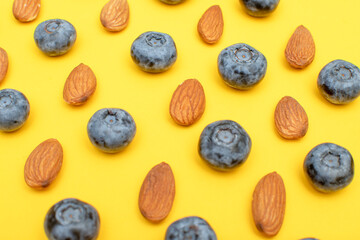 Fresh blueberry and almond nuts on yellow background	