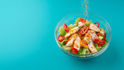 A glass blow of chicken salad on a blue background with falling spices, ai generated