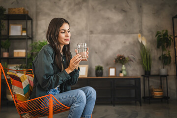Portrait of adult young women sit in a chair and hold glass of water