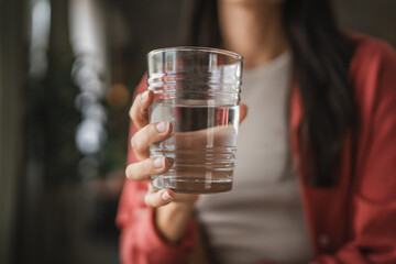 Close up of woman hand stand and hold glass of water at home