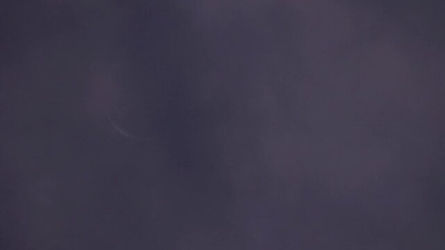 Tokyo, Japan -August 2, 2024: A crescent moon partially covered with Moving thin clouds at dawn
