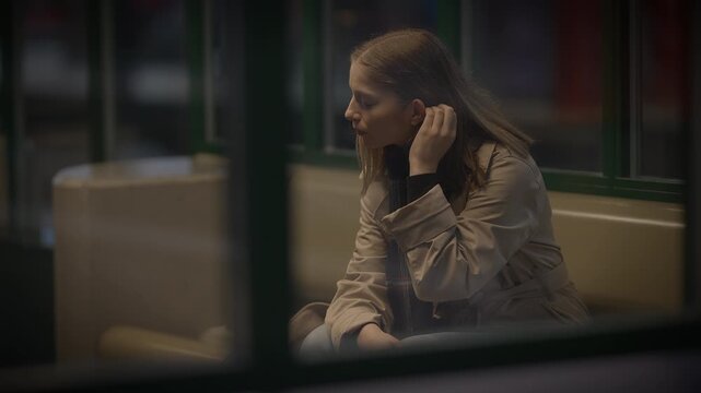 A woman sits by a window, lost in deep thought, reflecting solitude and introspection