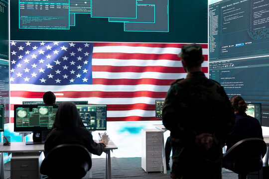 American army soldier working on servers and state secrets protection, safeguarding important hybrid war intelligence in high tech agency. Military official supervises hacking activity.