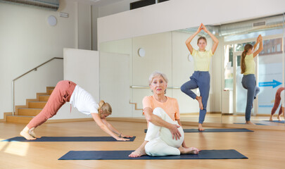Obraz premium Portrait of active woman practicing yoga in group, making twisting asana