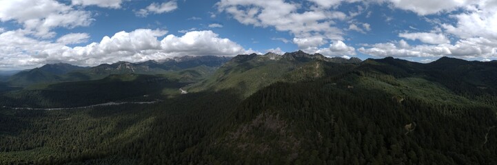 Panoramic View of Mountain Range and Forest Under a Partly Cloudy Sky