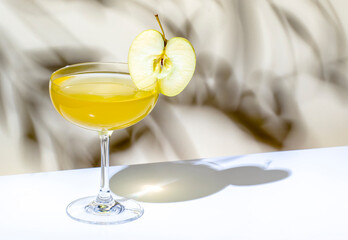 Yellow apple cocktail drink with vodka, gin, liqueur and syrup. on beige background, hard light
