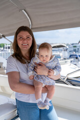 A woman joyfully holds her baby while enjoying a marina setting